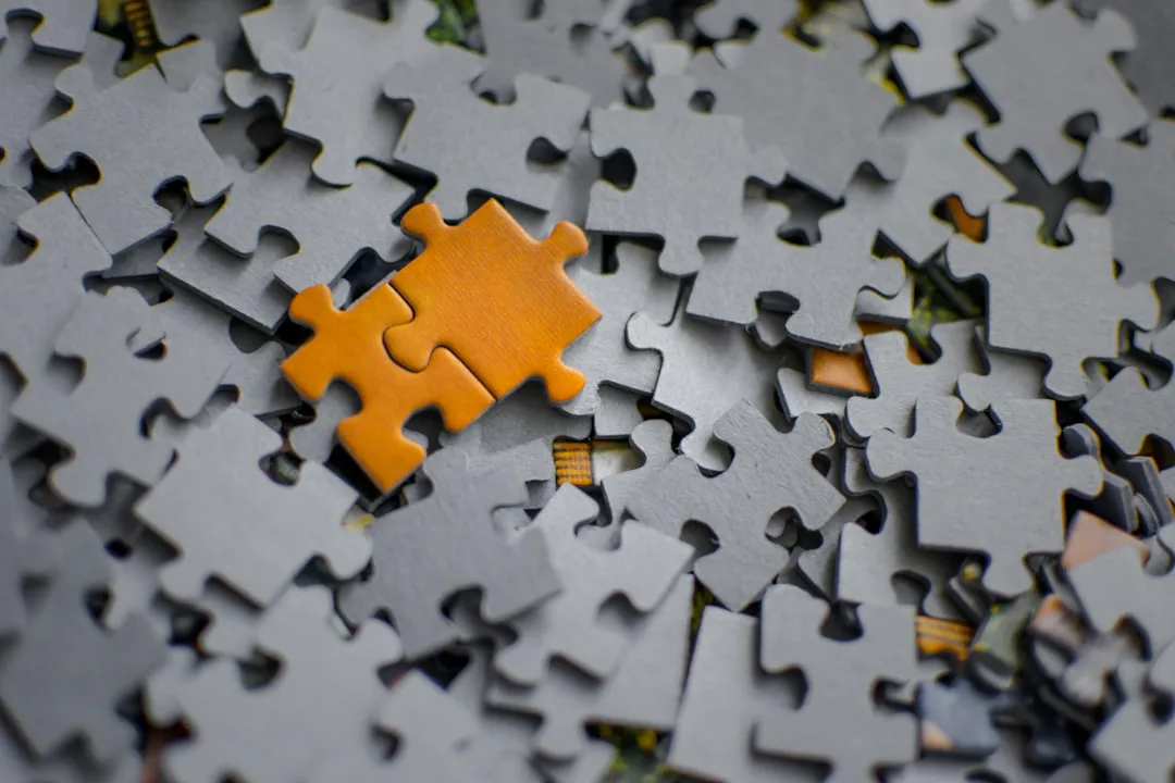 Subsidies combineren — A single orange puzzle piece rests on a pile of grey pieces.
