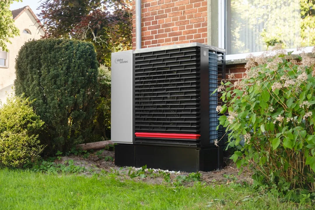 Hybride warmtepomp — Outdoor heat pump unit next to a brick building.